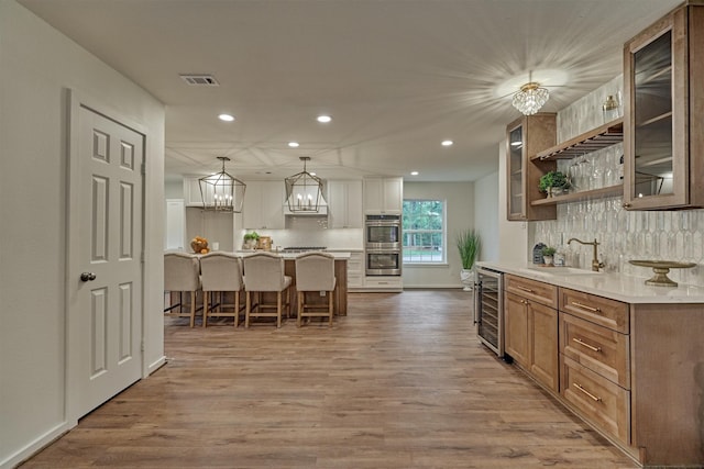 6326 Bayonne Dr, Spring, TX 77389 - kitchen featuring beverage cooler, a sink, double oven, recessed lighting, and wood finished floors