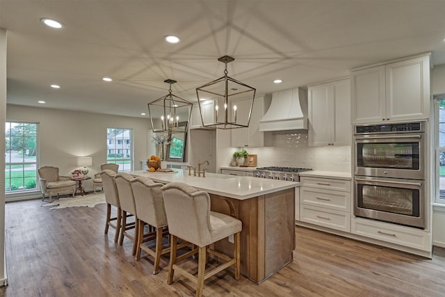 6326 Bayonne Dr, Spring, TX 77389 - kitchen with stainless steel appliances, custom range hood, recessed lighting, wood finished floors, and light countertops