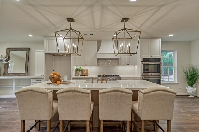 6326 Bayonne Dr, Spring, TX 77389 - kitchen with stainless steel double oven, a chandelier, custom range hood, a sink, and white cabinetry
