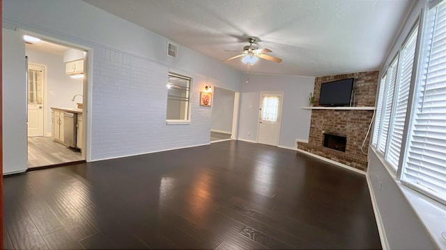 13419 Greenway Dr, Sugar Land, TX 77498 - unfurnished living room featuring a ceiling fan, a fireplace, wood finished floors, baseboards, and brick wall