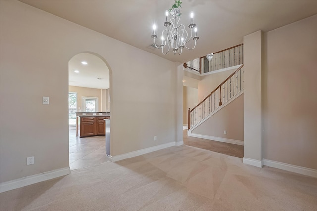 4131 Regal Stone Ln, Sugar Land, TX 77479 - spare room with arched walkways, light colored carpet, baseboards, a chandelier, and stairs