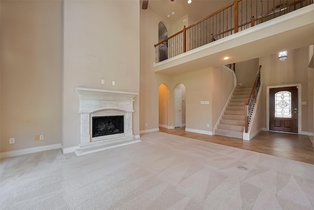 4131 Regal Stone Ln, Sugar Land, TX 77479 - unfurnished living room featuring carpet floors, a high ceiling, stairs, arched walkways, and baseboards