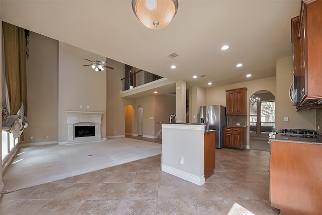 4131 Regal Stone Ln, Sugar Land, TX 77479 - kitchen with arched walkways, stainless steel fridge with ice dispenser, brown cabinets, a ceiling fan, and open floor plan
