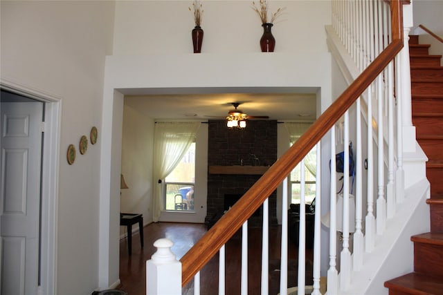 3231 Brinton Trails Ln, Katy, TX 77494 - stairs featuring a ceiling fan, a large fireplace, wood finished floors, and a towering ceiling