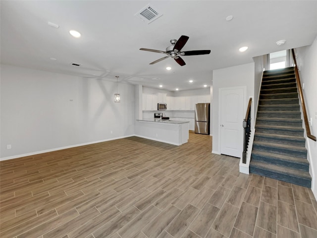 8022 Scanlan Trce, Missouri City, TX 77459 - unfurnished living room featuring ceiling fan, stairway, baseboards, light wood finished floors, and recessed lighting