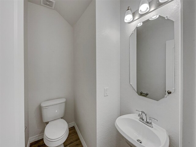 8022 Scanlan Trce, Missouri City, TX 77459 - half bath featuring a sink, toilet, lofted ceiling, baseboards, and wood finished floors