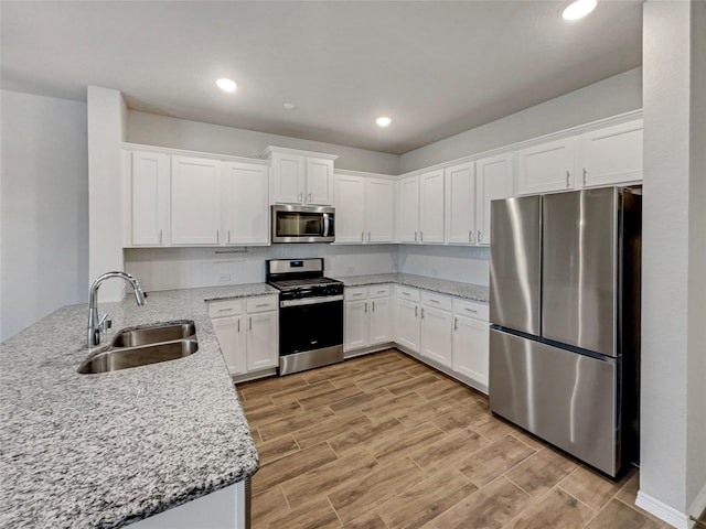 8022 Scanlan Trce, Missouri City, TX 77459 - kitchen with stainless steel appliances, a sink, light wood-type flooring, white cabinetry, and light stone counters