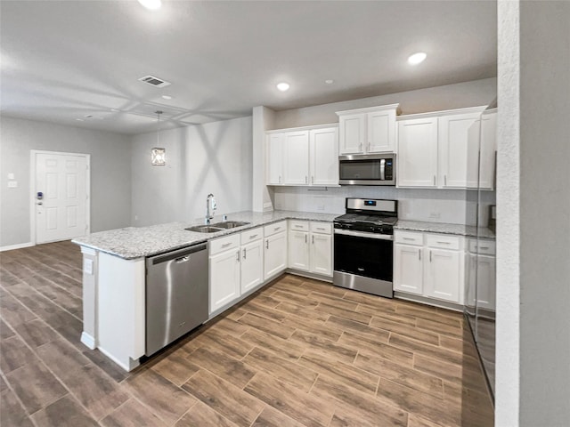 8022 Scanlan Trce, Missouri City, TX 77459 - kitchen with stainless steel appliances, a sink, a peninsula, wood finished floors, and white cabinetry
