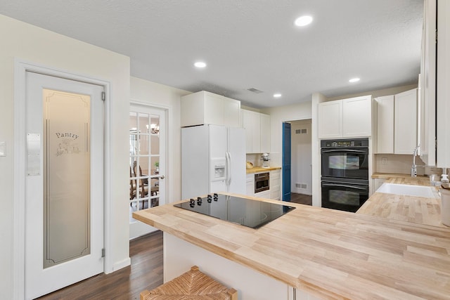 7514 Renmark Ln, Houston, TX 77070 - kitchen with butcher block counters, black appliances, white cabinets, dark wood-type flooring, and recessed lighting