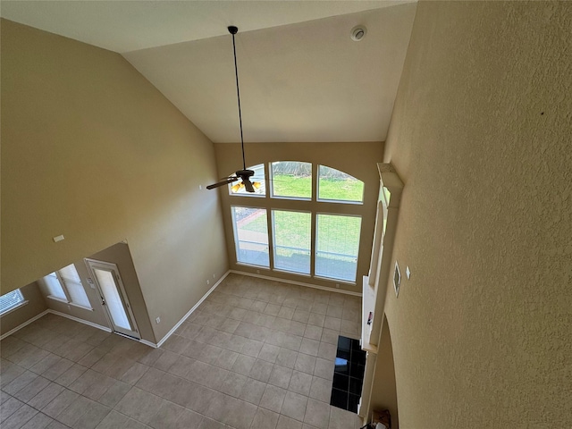 11703 Sterling Brook St, Pearland, TX 77584 - unfurnished dining area with tile patterned flooring, ceiling fan, a textured wall, baseboards, and high vaulted ceiling