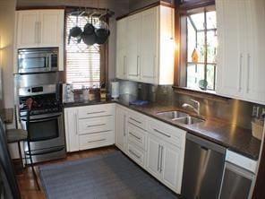 1401 Truxillo St, Houston, TX 77004 - kitchen featuring stainless steel appliances, white cabinets, dark countertops, a sink, and a chandelier