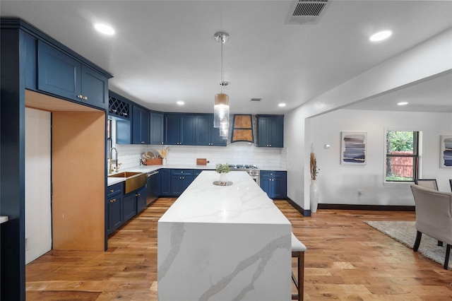 701 W 39th St, Houston, TX 77018 - kitchen featuring blue cabinetry, a sink, custom exhaust hood, a kitchen island, and tasteful backsplash