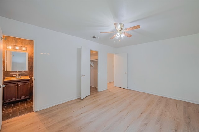 12206 Ashcroft Dr, Houston, TX 77035 - unfurnished bedroom featuring light wood-type flooring, a walk in closet, connected bathroom, baseboards, and a closet
