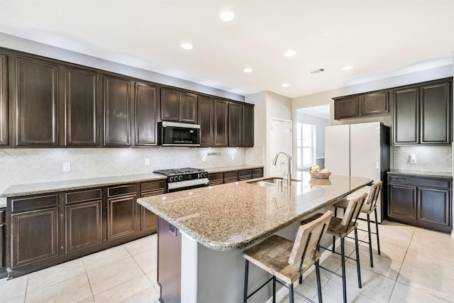16802 Cherokee Lake Ln, Houston, TX 77044 - kitchen with a sink, stainless steel microwave, gas range, light stone counters, and backsplash