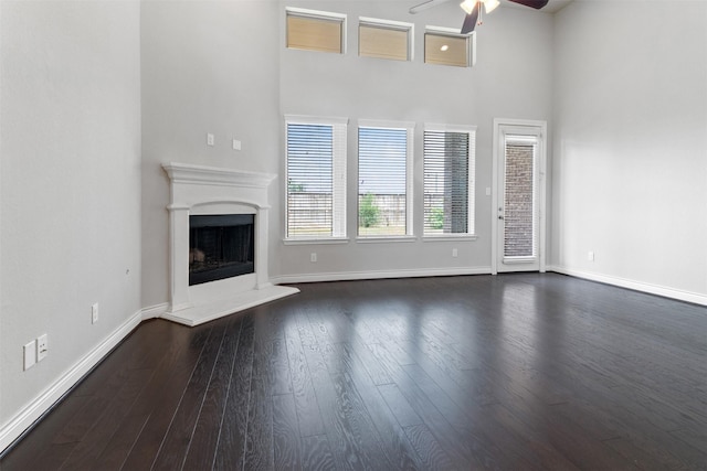 4926 Thunder Creek Ln, Sugar Land, TX 77479 - unfurnished living room featuring ceiling fan, a fireplace with raised hearth, a towering ceiling, dark wood-type flooring, and baseboards