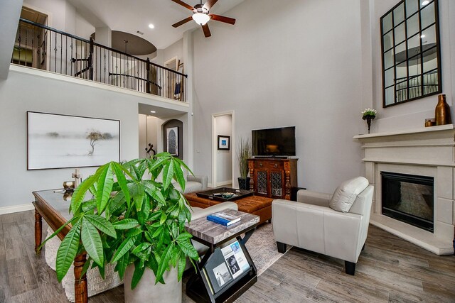29016 Concan Crossing Ct, Katy, TX 77494 - living area with a towering ceiling, a ceiling fan, wood finished floors, a glass covered fireplace, and baseboards