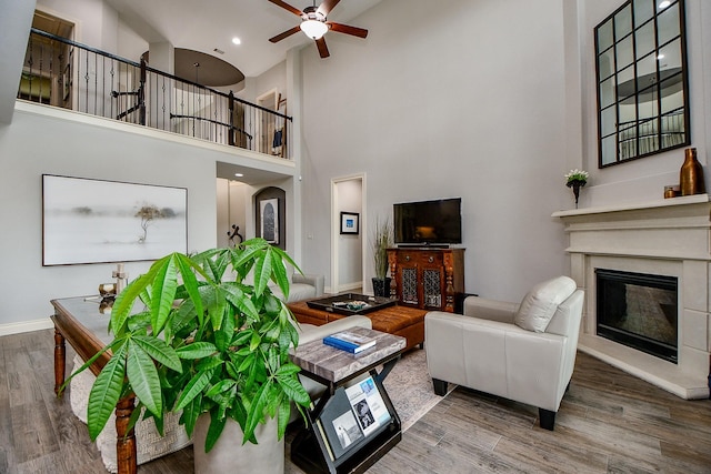 29016 Concan Crossing Ct, Katy, TX 77494 - living room with a towering ceiling, ceiling fan, wood finished floors, a glass covered fireplace, and baseboards