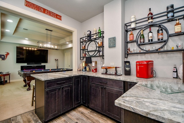 29016 Concan Crossing Ct, Katy, TX 77494 - kitchen with light stone countertops, a peninsula, dark brown cabinetry, light wood-type flooring, and open shelves