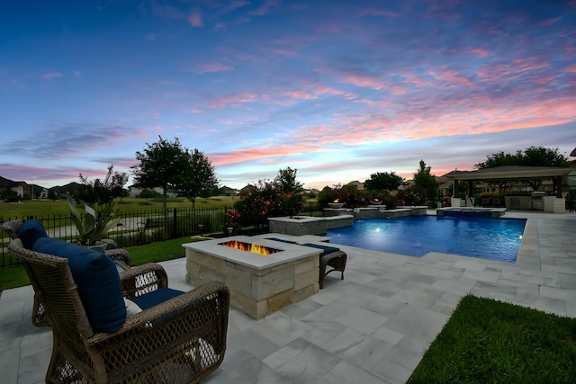 29016 Concan Crossing Ct, Katy, TX 77494 - pool at dusk featuring an outdoor fire pit, a pool with connected hot tub, a patio, and a fenced backyard
