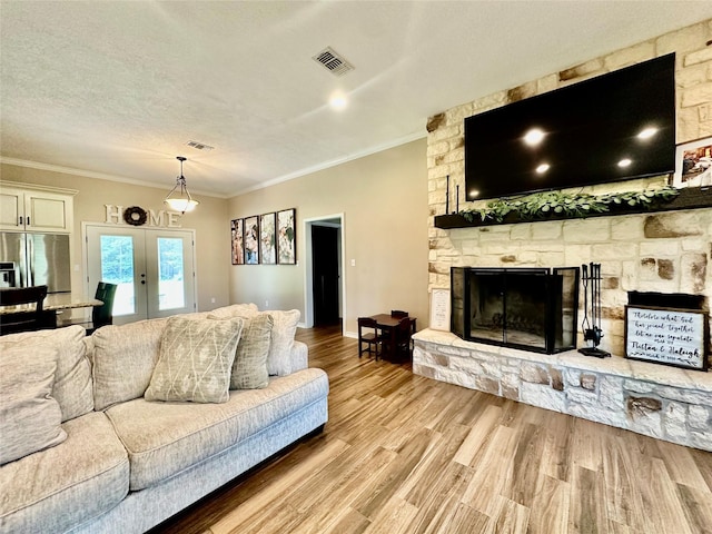 4815 Fm 2827th Rd, Warren, TX 77664 - living area with crown molding, wood finished floors, a stone fireplace, french doors, and a textured ceiling