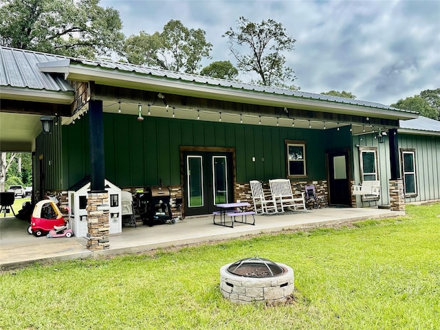 4815 Fm 2827th Rd, Warren, TX 77664 - rear view of property featuring board and batten siding, a yard, an outdoor fire pit, a patio, and french doors