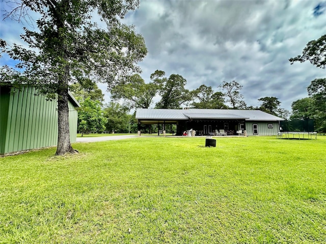 4815 Fm 2827th Rd, Warren, TX 77664 - view of green lawn with a trampoline, a pole building, an outdoor structure, and a carport