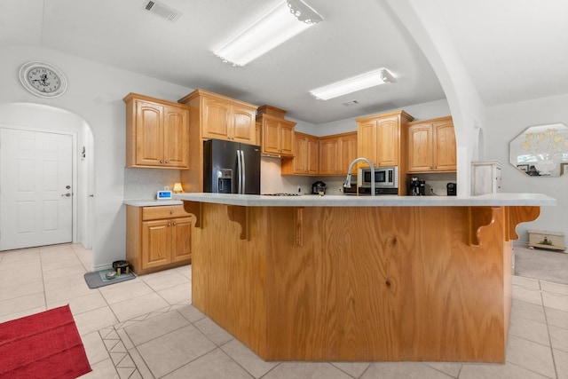 197 Westwood Dr E, Trinity, TX 75862 - kitchen featuring black refrigerator with ice dispenser, arched walkways, a breakfast bar area, and stainless steel microwave