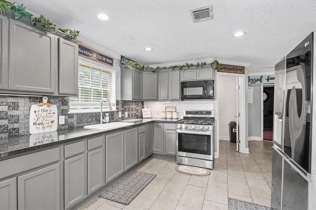 1406 Grand Valley Dr, Houston, TX 77090 - kitchen with gas stove, black microwave, a sink, gray cabinets, and refrigerator