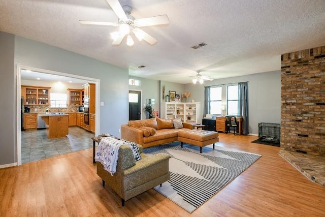 22035 Buescher Rd, Tomball, TX 77377 - living room featuring ceiling fan, a textured ceiling, light wood-style flooring, a fireplace, and baseboards
