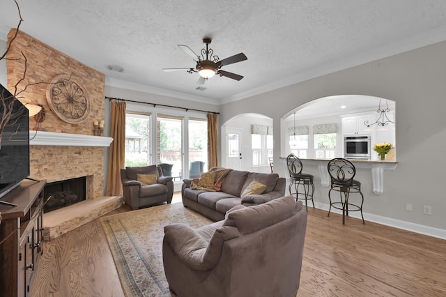 7 Newland Ct, The Woodlands, TX 77382 - living area featuring ceiling fan, arched walkways, light wood-type flooring, a textured ceiling, and ornamental molding
