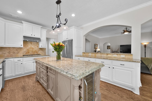 7 Newland Ct, The Woodlands, TX 77382 - kitchen with freestanding refrigerator, a center island, ceiling fan, light wood-type flooring, and light stone countertops