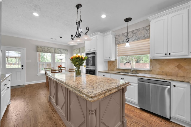 7 Newland Ct, The Woodlands, TX 77382 - kitchen with stainless steel appliances, a sink, wood finished floors, a kitchen island, and decorative backsplash