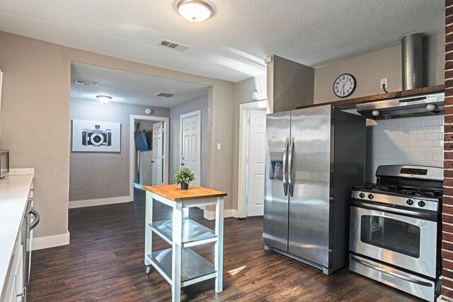 5213 Claremont St, Houston, TX 77023 - kitchen with appliances with stainless steel finishes, range hood, baseboards, dark wood finished floors, and wooden counters