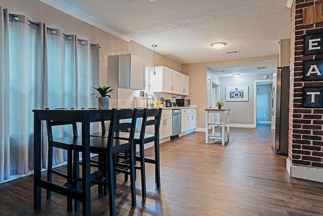 5213 Claremont St, Houston, TX 77023 - dining room with dark wood-style flooring, a textured ceiling, baseboards, and crown molding
