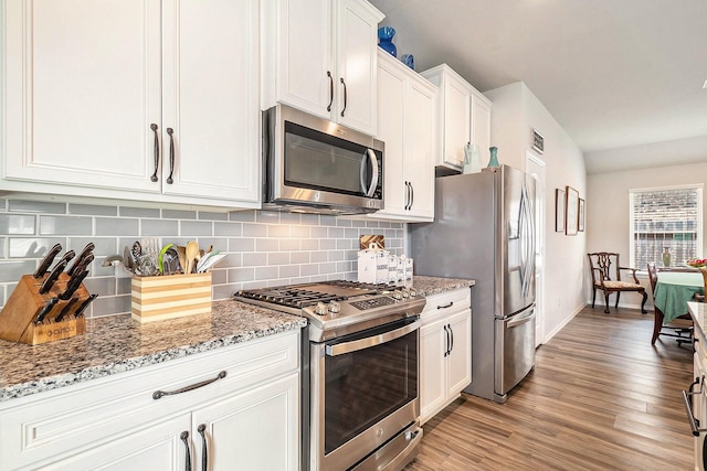 9521 Mountain Maple Pl, Conroe, TX 77385 - kitchen featuring stainless steel appliances, decorative backsplash, white cabinets, baseboards, and light wood-style flooring