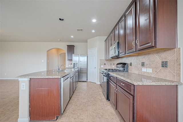 3722 Glover Meadows Ln, Houston, TX 77047 - kitchen with stainless steel appliances, arched walkways, light tile patterned flooring, a sink, and an island with sink