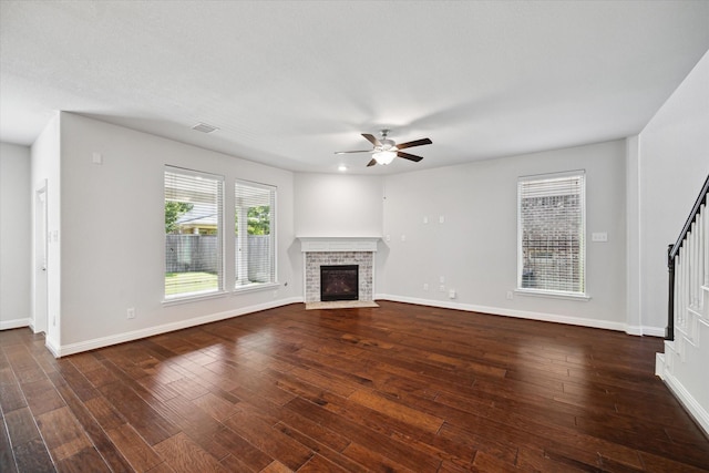 12 Centennial Ridge Pl, Magnolia, TX 77354 - unfurnished living room featuring a brick fireplace, ceiling fan, baseboards, and dark wood-type flooring