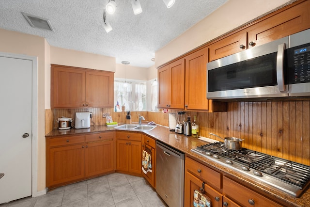 19527 Enchanted Spring Dr, Spring, TX 77388 - kitchen with appliances with stainless steel finishes, a sink, brown cabinets, light tile patterned floors, and backsplash