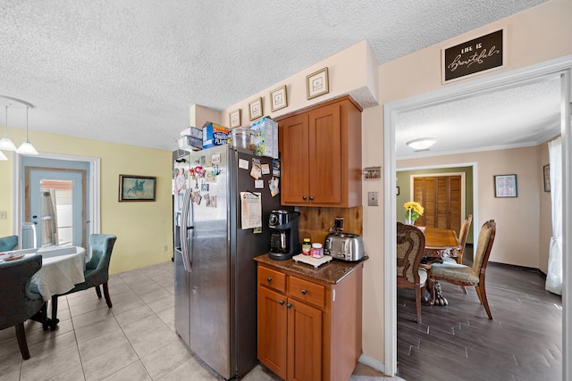 19527 Enchanted Spring Dr, Spring, TX 77388 - kitchen featuring stainless steel fridge, a textured ceiling, brown cabinets, and pendant lighting