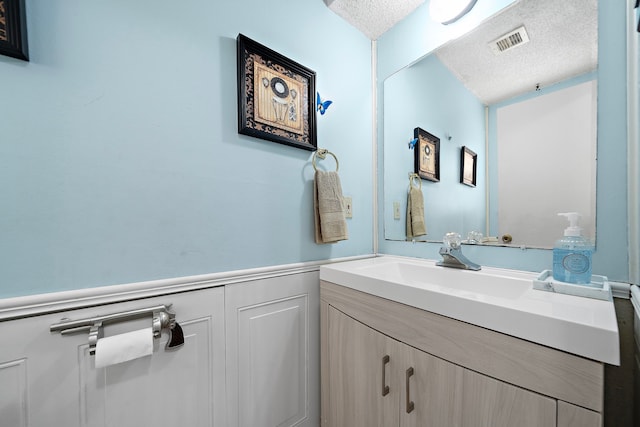 19527 Enchanted Spring Dr, Spring, TX 77388 - bathroom featuring a textured ceiling, vanity, and wainscoting