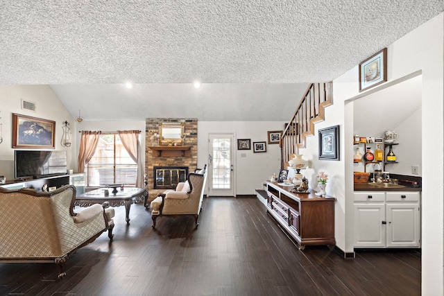 19527 Enchanted Spring Dr, Spring, TX 77388 - living room featuring vaulted ceiling, a textured ceiling, dark wood-type flooring, a fireplace, and stairway