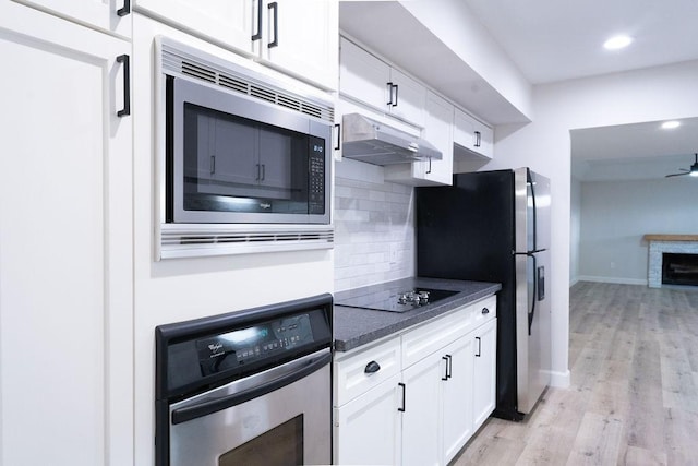 2243 W Alabama St Unit 10, Houston, TX 77098 - kitchen featuring appliances with stainless steel finishes, under cabinet range hood, backsplash, light wood-type flooring, and white cabinets