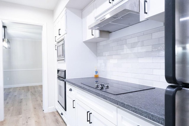 2243 W Alabama St Unit 10, Houston, TX 77098 - kitchen with under cabinet range hood, appliances with stainless steel finishes, tasteful backsplash, white cabinets, and light wood-style floors