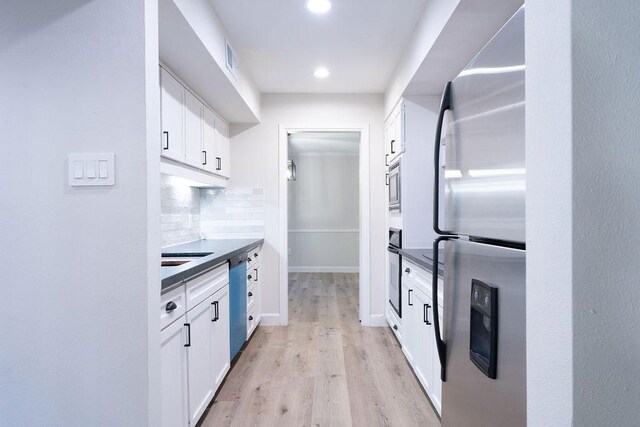 2243 W Alabama St Unit 10, Houston, TX 77098 - kitchen featuring stainless steel appliances, light wood-style flooring, white cabinetry, decorative backsplash, and recessed lighting