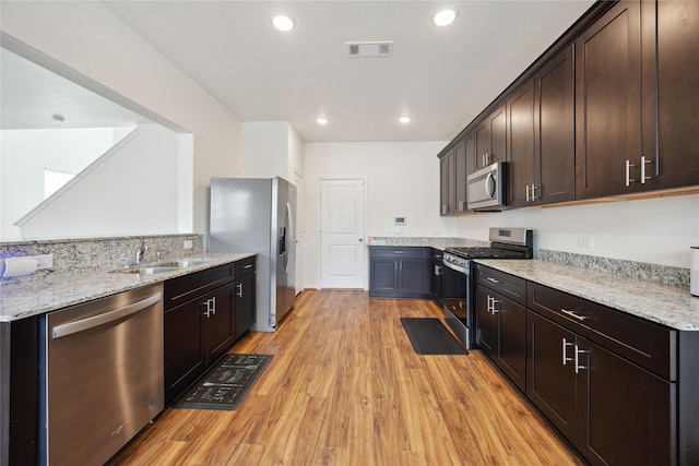 10127 Clearwick St, Houston, TX 77034 - kitchen featuring stainless steel appliances, a sink, dark brown cabinets, light stone counters, and recessed lighting