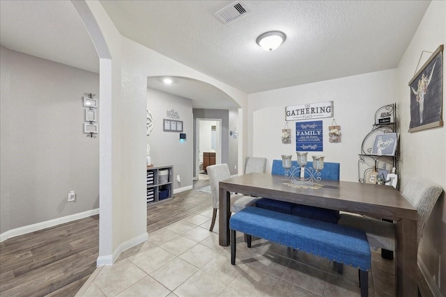6011 Treasure Cove Rd, Cove, TX 77523 - dining space with arched walkways, a textured ceiling, light wood finished floors, and baseboards