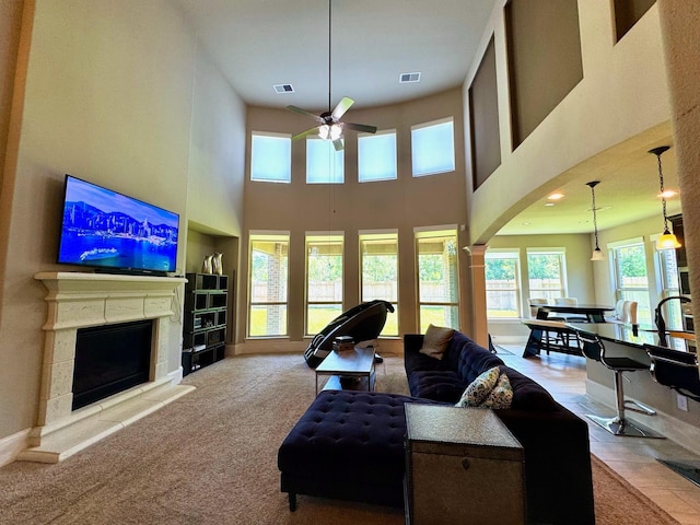 7739 Augusta Creek Ct, Spring, TX 77389 - living room with a ceiling fan, a fireplace with raised hearth, a towering ceiling, arched walkways, and carpet