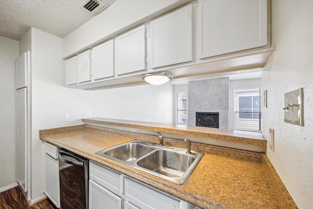 6701 Sands Point Dr Unit 129, Houston, TX 77074 - kitchen featuring a sink, dishwasher, a textured ceiling, white cabinetry, and a high end fireplace