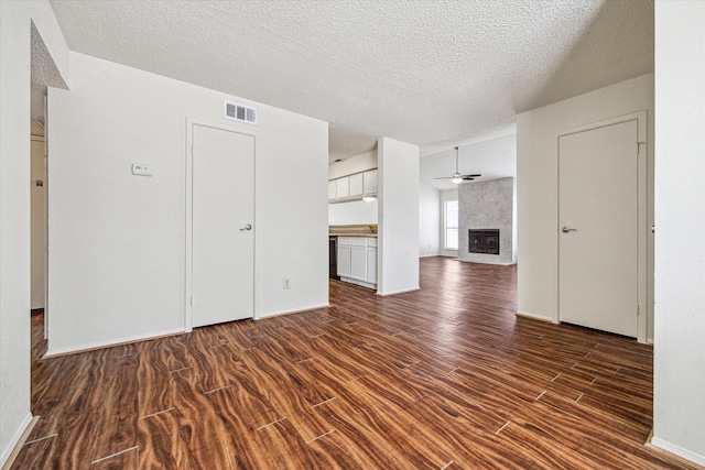 6701 Sands Point Dr Unit 129, Houston, TX 77074 - unfurnished living room featuring a tiled fireplace, dark wood-style flooring, a textured ceiling, baseboards, and a ceiling fan