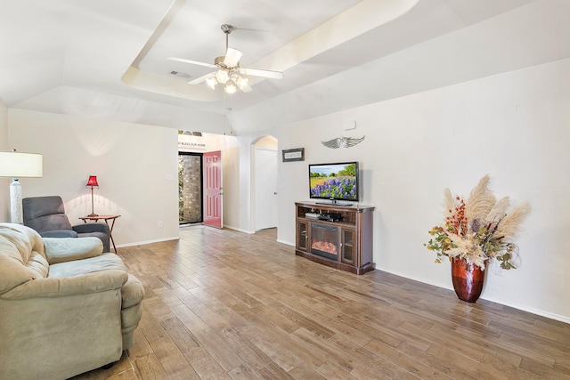 414 Laurel Sage Dr, Houston, TX 77339 - living room featuring a tray ceiling, arched walkways, wood finished floors, a ceiling fan, and baseboards